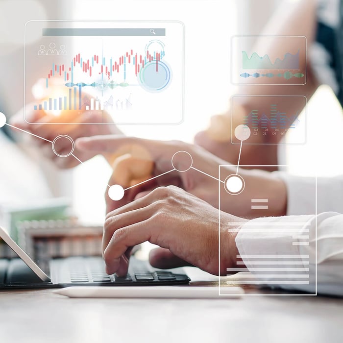 Two people are working together on a tablet with a keyboard. Graphic overlays display analytical data.