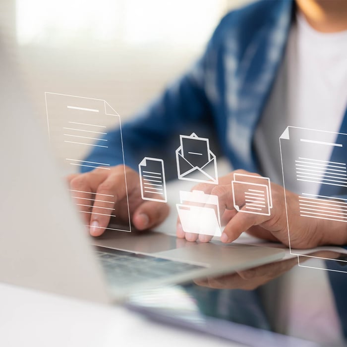 Hands typing on a laptop, with transparent icons for documents, folders, and email (data management) floating above.
